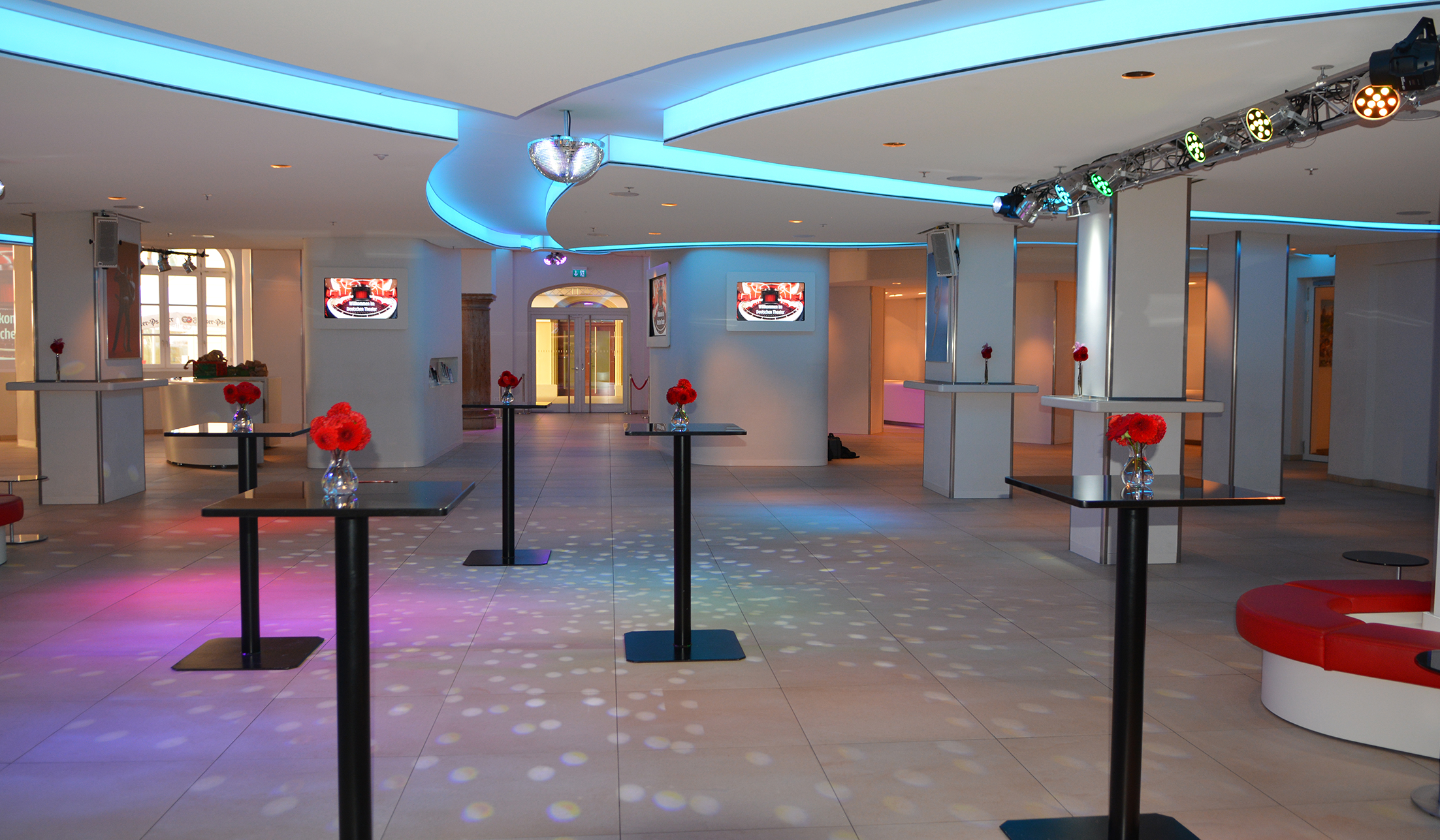 stilvoll beleuchtetes Foyer mit Tischen udn roten Blumen im deutschen Theater München